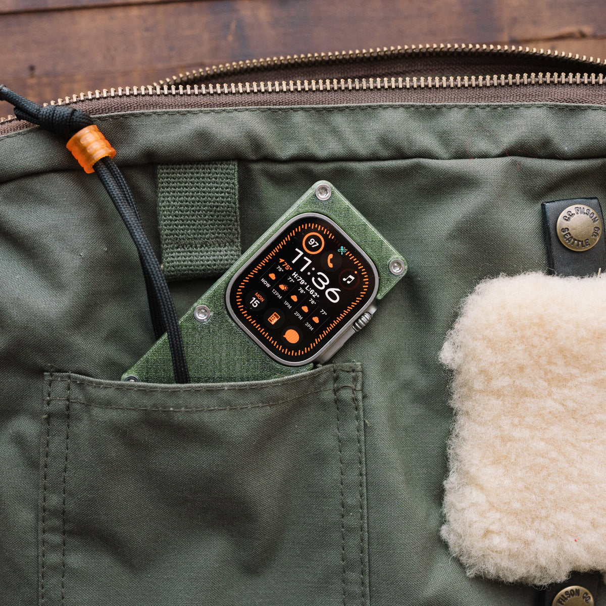 Apple Watch Ultra in an olive green miniPhone Ultra case tucked into a green jacket pocket.