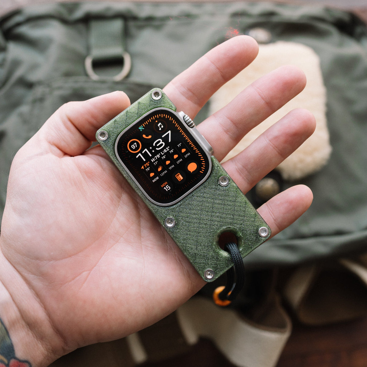 Apple Watch Ultra in an olive green miniPhone Ultra case resting in an open palm.